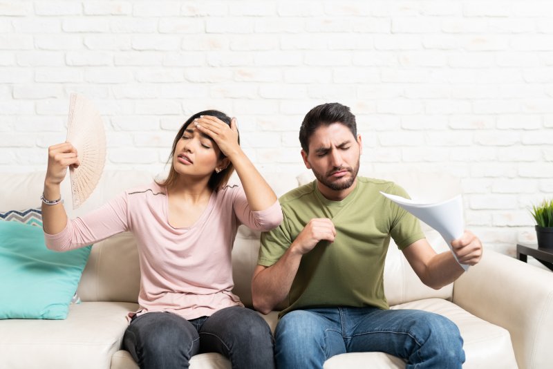 a couple feeling hot while sitting on their couch